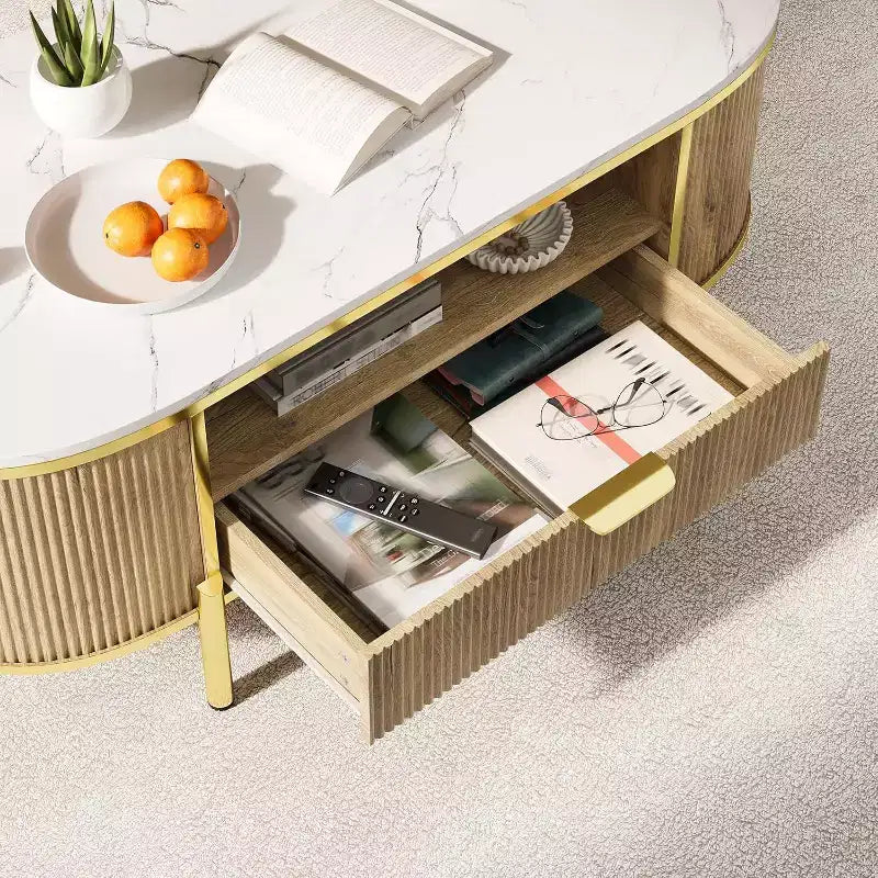 Tavolino da caffè ovale scanalato da 48" con piano in finto marmo, gambe dorate e cassetto portaoggetti nascosto